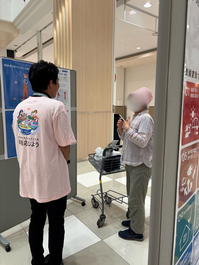 写真：職員が来場者に「15の適応アクション」を説明している