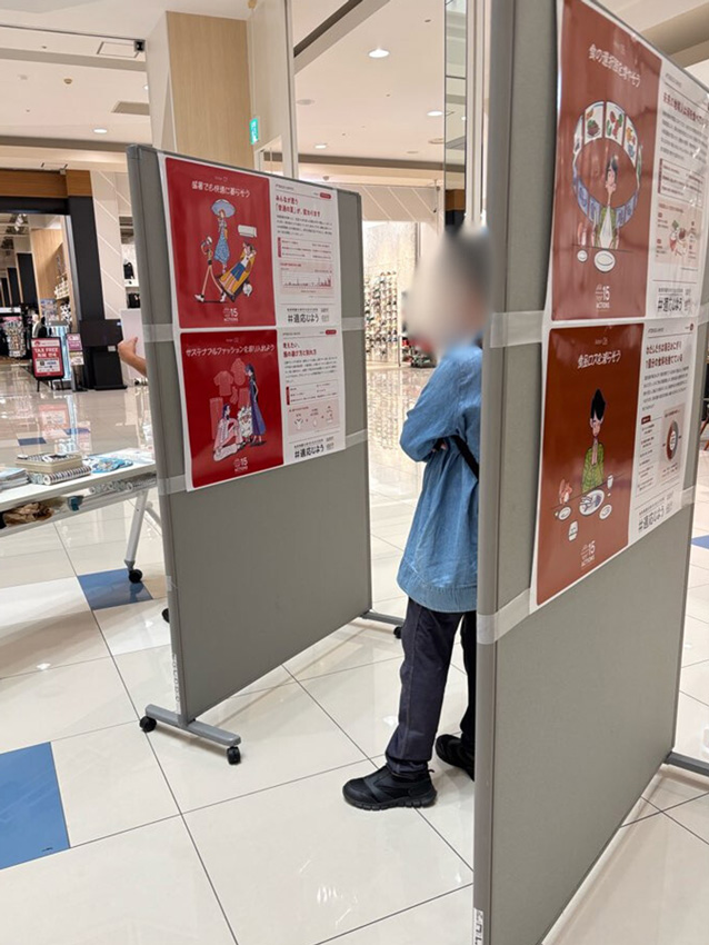 写真：グラフィカルなイラストを使用したポスターに興味津々の来場者